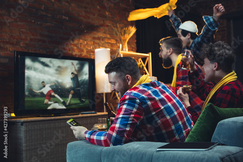 Fototapeta Naklejka Na Ścianę i Meble -  Group of friends watching TV, sport match together. Emotional fans cheering for favourite team, watching on exciting game. Concept of friendship, leisure activity, emotions