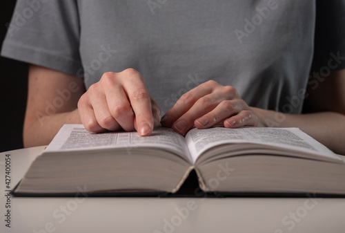 Female student hands close up, pointing on text in book or textbook, searching for information and reading at night photo