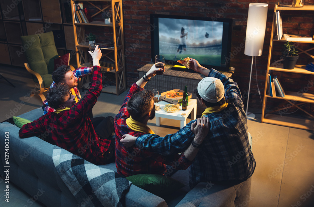 Group of friends watching TV, sport match together. Emotional fans cheering for favourite team, watching on exciting game. Concept of friendship, leisure activity, emotions
