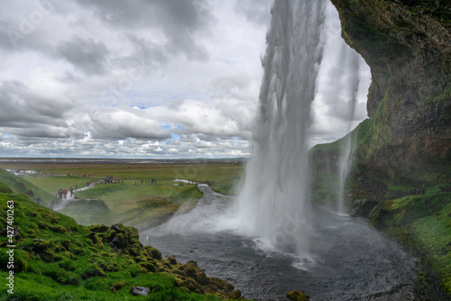 View from behind the Seljalandsfoss waterfall in Iceland on a cloudy day.