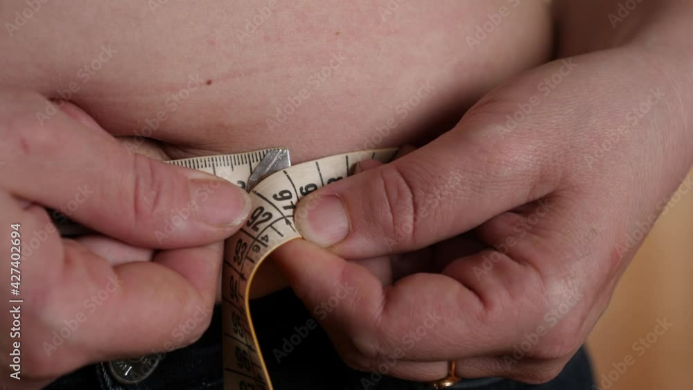 Hands measuring waist with tape. The problem of overweight and healthy eating Hands measuring waist with tape. The problem of overweight and healthy eating