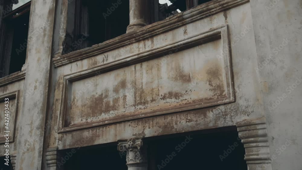 Dirty facade with columns and decor of old abandoned building with broken windows on cloudy spring day closeup aerial view Dirty facade with columns and decor of old abandoned building with broken windows on cloudy spring day closeup aerial view