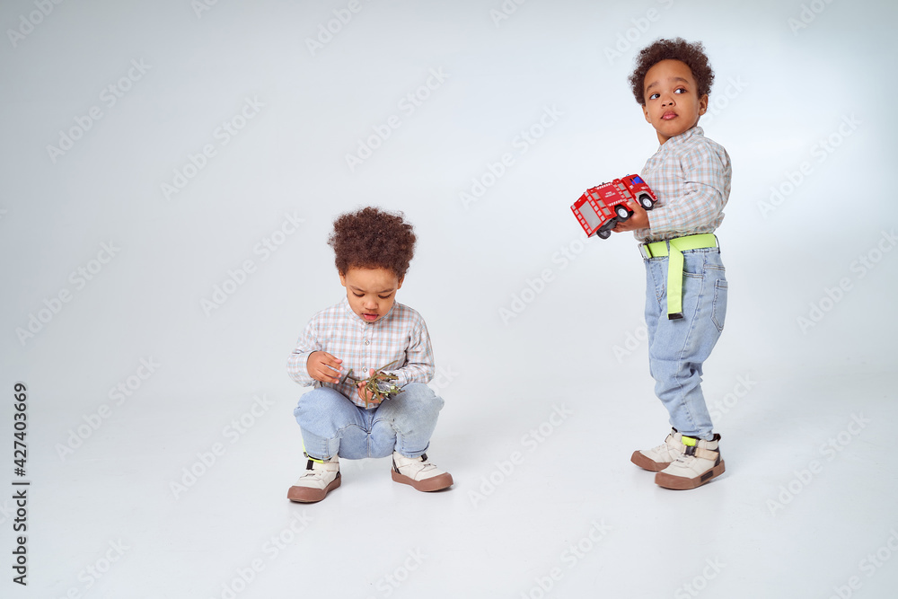Two little African-American boys with toys on a white background Two little African-American boys with toys on a white background