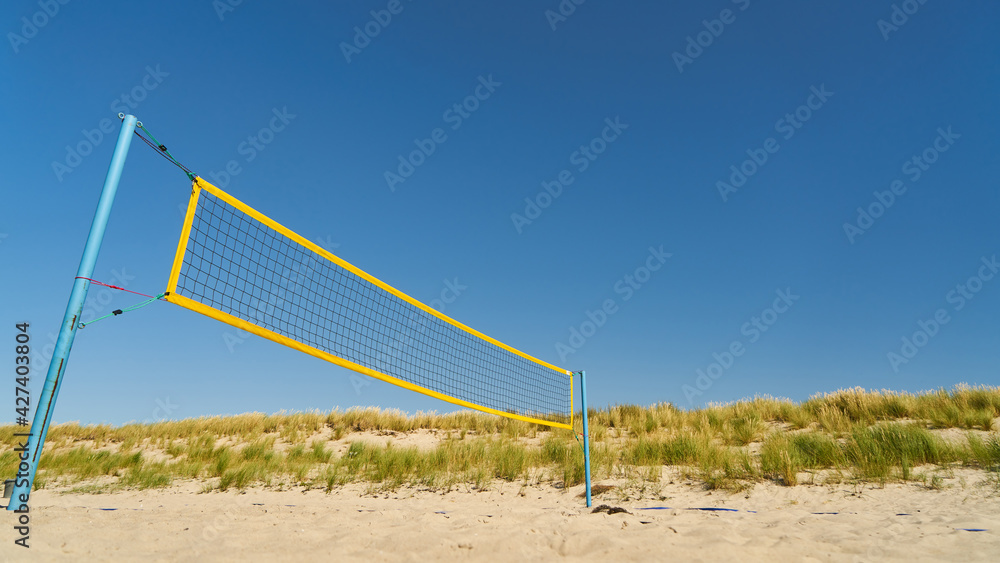 Volleyball net on sandy beach against a blue sky Volleyball net on sandy beach against a blue sky