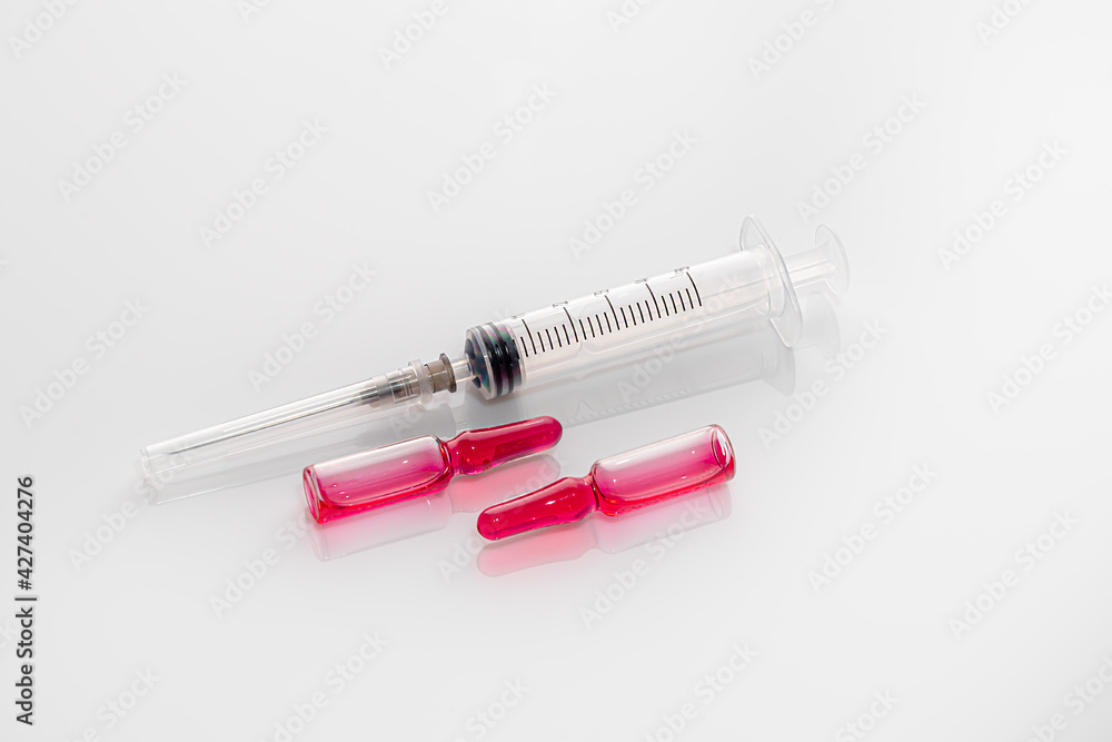 Ampoules with a medicine and a syringe on a light background. Coronavirus vaccine. Medical concept. Isolate. Ampoules with a medicine and a syringe on a light background. Coronavirus vaccine. Medical concept. Isolate.