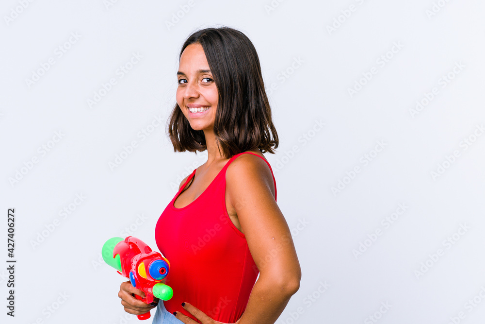 Young mixed race woman holding a water gun isolated confident keeping hands on hips. Young mixed race woman holding a water gun isolated confident keeping hands on hips.