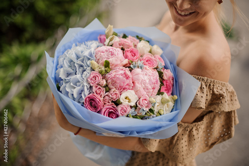 gorgeous large bouquet of multi-colored flowers in the hands of smiling woman