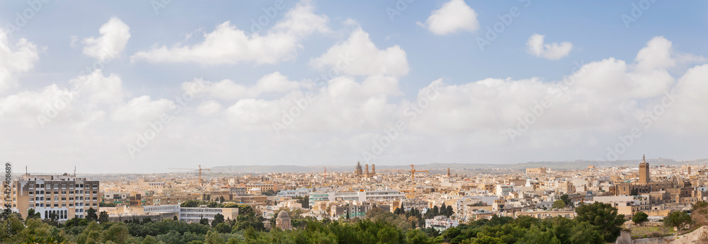 Panorama of Valletta, capital of Malta. Cityscape with ancient buildings, domes of church, construction cranes on sunny day.