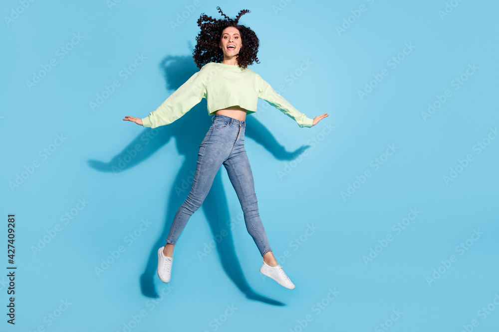 Full size photo of carefree pretty girl jumping make star figure have fun isolated on blue color background Full size photo of carefree pretty girl jumping make star figure have fun isolated on blue color background