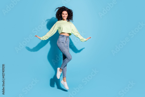 Full size portrait of adorable satisfied person jumping hands fly beaming smile isolated on blue color background