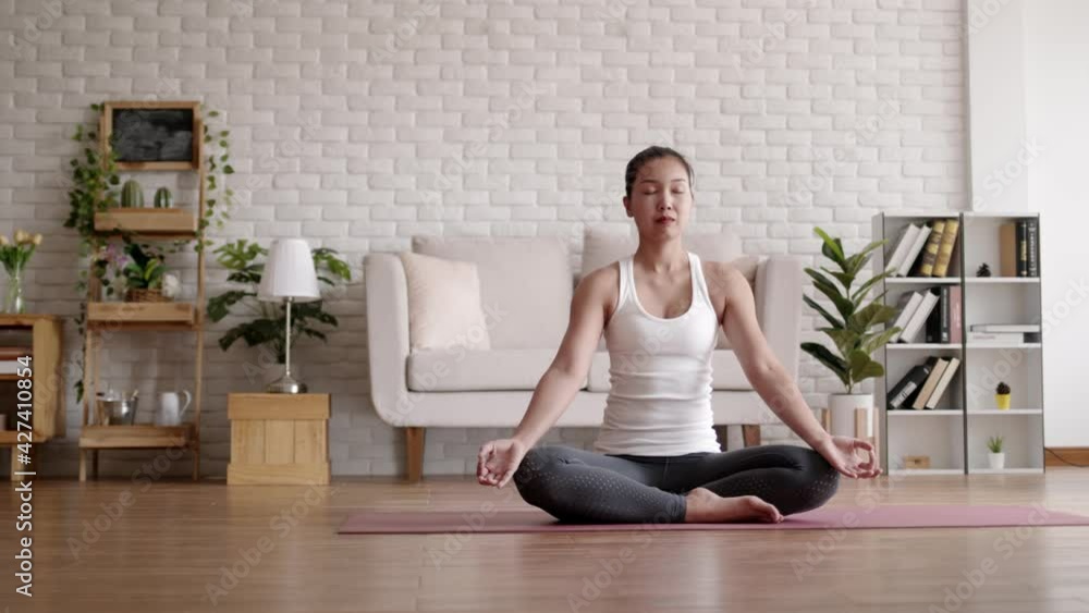 Asian woman practicing meditating yoga in home. Asian woman practicing meditating yoga in home.