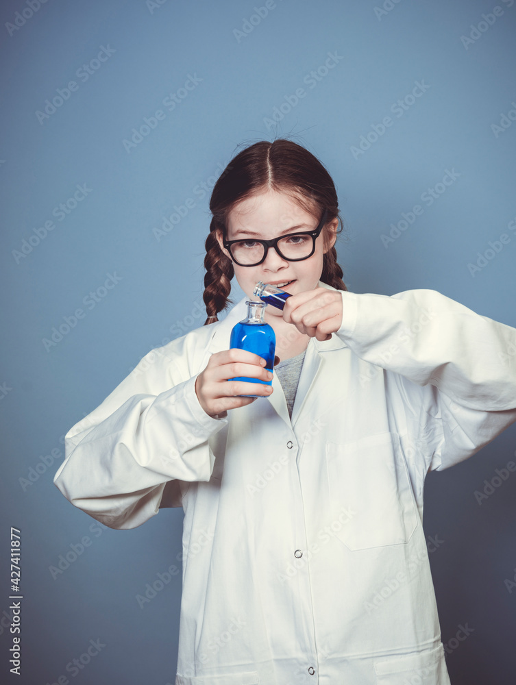 pretty girl with two braids is dressed as scientist and experimenting with blue liquids wearing black glasses in front of blue background pretty girl with two braids is dressed as scientist and experimenting with blue liquids wearing black glasses in front of blue background