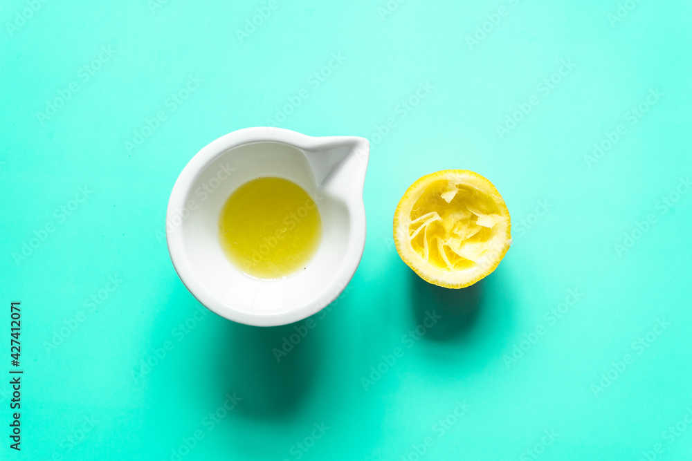 Ein halbierte ausgepresste Zitrone und Zitronensaft in einer weißen Schüssel. Draufsicht, minzgrün Hintergrund. Ein halbierte ausgepresste Zitrone und Zitronensaft in einer weißen Schüssel. Draufsicht, minzgrün Hintergrund.