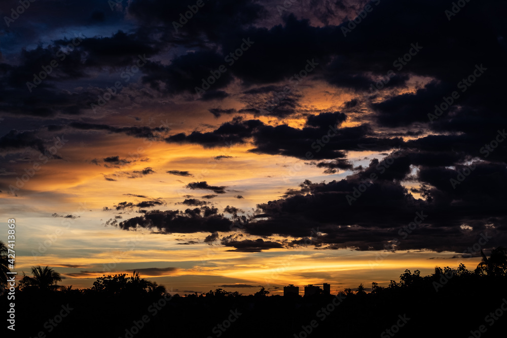 Panorama Cityscape at sunset with large river at foreground and strom clouds at background in Thailand.