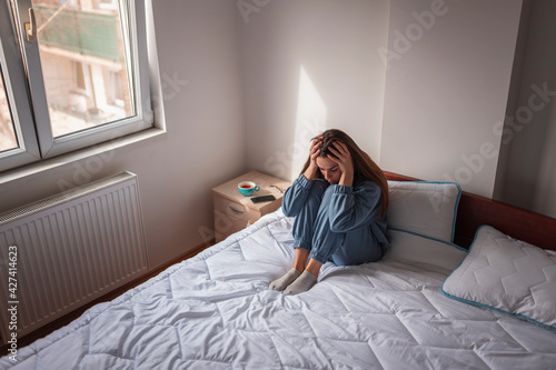 Schilderij op canvas Upset woman holding head in hands depressed in bed