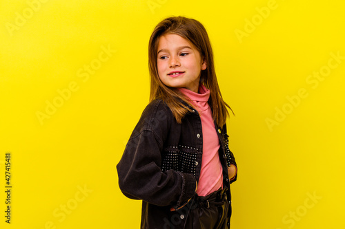 Little caucasian girl isolated on yellow background laughs happily and has fun keeping hands on stomach. © Asier