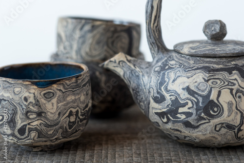 Handmade ceramics in the style of wabi sabi. Clay teapot and cup with an abstract pattern. photo