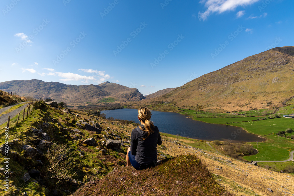 Woman Sitting and Admiring a Lake and Mountain Landscape