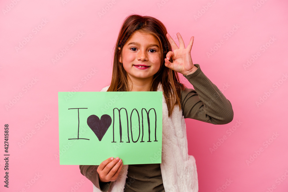 Little girl holding an I love mum placard isolated on pink background Little girl holding an I love mum placard isolated on pink background