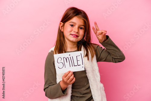 Young little girl holding a smile banner on pink background
