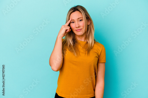 Young mixed race woman isolated on blue background pointing temple with finger, thinking, focused on a task. © Asier