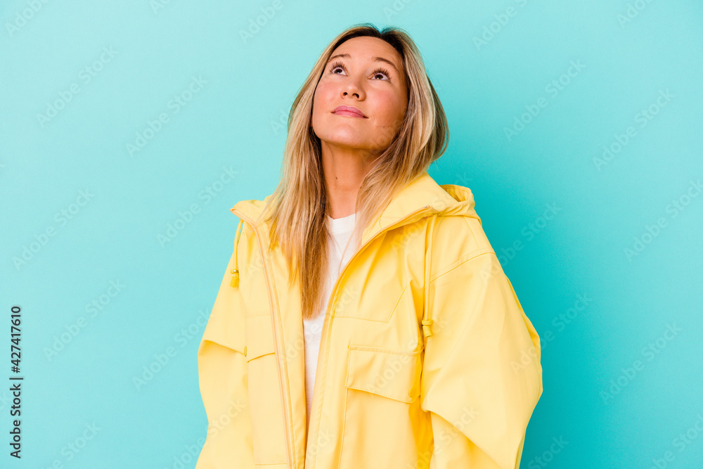 Young mixed race woman isolated on blue background relaxed and happy laughing, neck stretched showing teeth. Young mixed race woman isolated on blue background relaxed and happy laughing, neck stretched showing teeth.