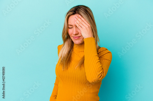 Young mixed race woman isolated on blue background having a head ache, touching front of the face.