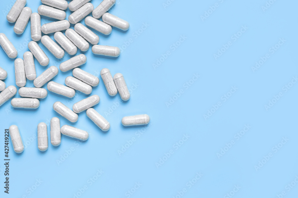 Pills, tablets, vitamins, food supplement in white capsules on blue background. Health concept, vitamin deficiency, avitaminosis, medical pharmaceutical background. Flat lay top view copy space