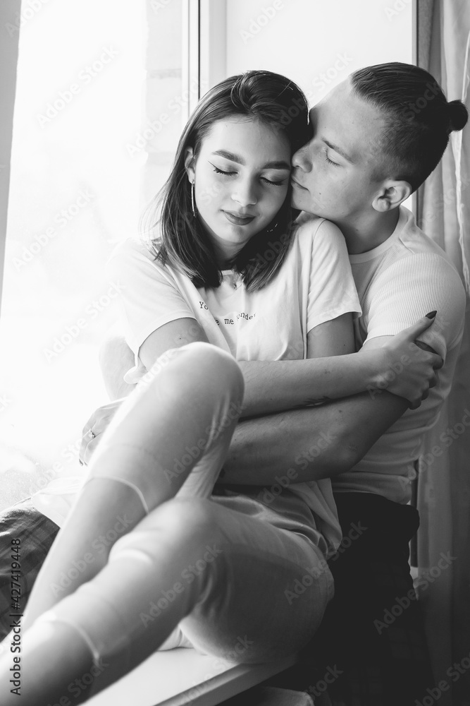 Couple at home dressed in home clothes sitting on the windowsill black and white photo
Couple at home dressed in home clothes sitting on the windowsill black and white photo