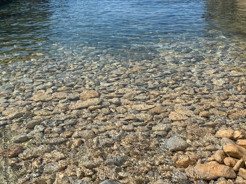 Sea transparent water, crystal clear sea water surface on pebbles beach. Zen landscape, mediation of nature, beautiful seascape, sunlight on stones.