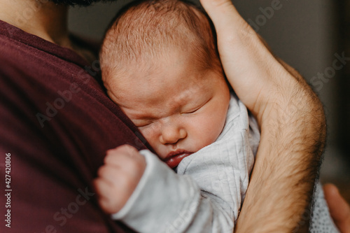 home photos of a newborn baby in the arms of father. Selective focus, noise effect