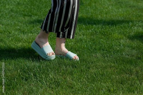 Girl in flip flop walking on a grass