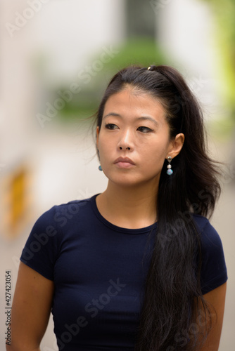 Portrait of beautiful rebel Asian woman thinking outdoors