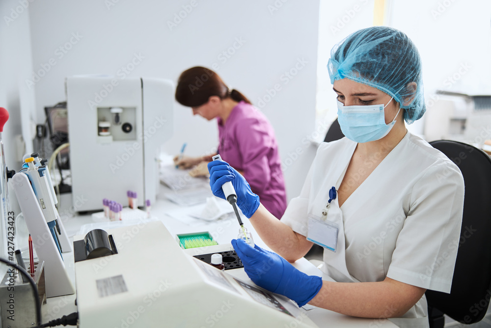 Fototapeta premium Young lab worker performing a biochemical analysis in latex gloves