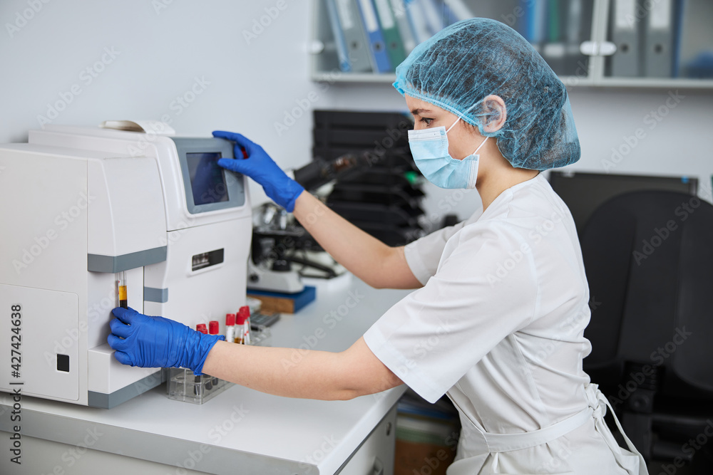 Experienced biochemist using a hematology analyzer for a blood analysis Experienced biochemist using a hematology analyzer for a blood analysis