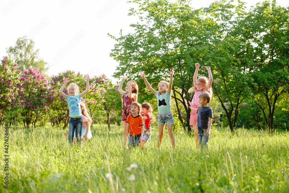 A group of happy children of boys and girls run in the Park on the grass on a Sunny summer day . The concept of ethnic friendship, peace, kindness, childhood