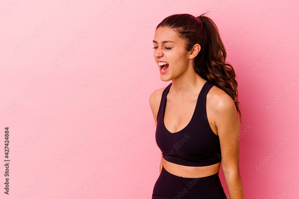 Young sport Indian woman isolated on pink background shouting towards a copy space Young sport Indian woman isolated on pink background shouting towards a copy space