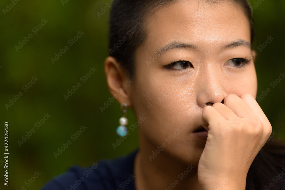Close-up portrait of beautiful rebel Asian woman face thinking outdoors Close-up portrait of beautiful rebel Asian woman face thinking outdoors