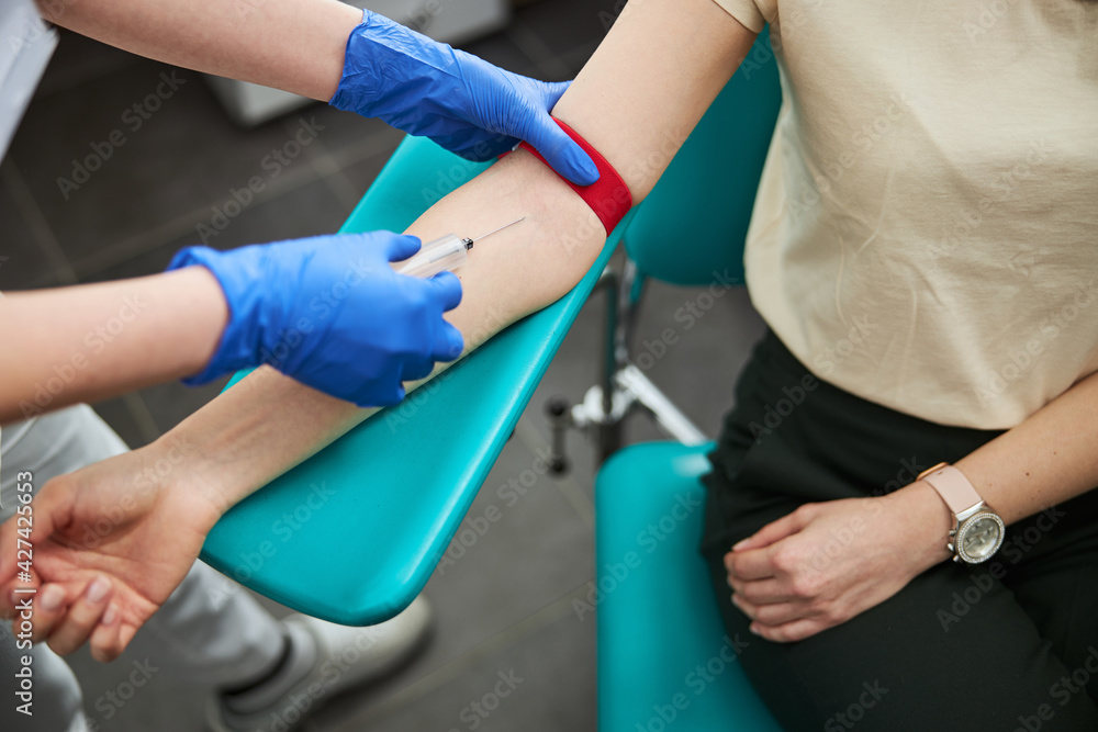Professional female phlebotomist performing a venipuncture procedure