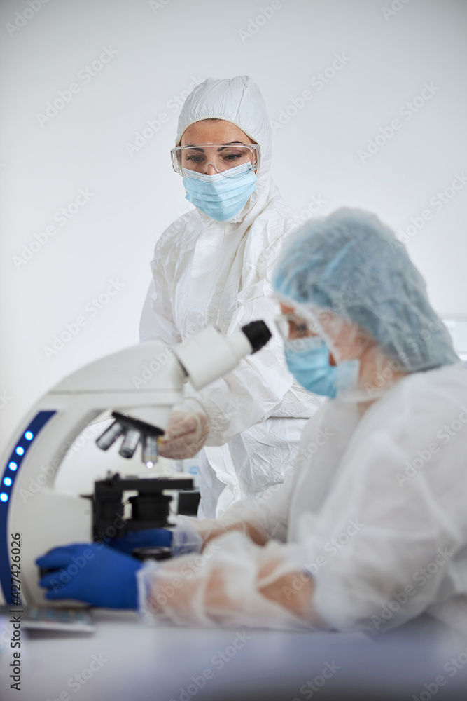 Scientists in hazmat suits examining a viral specimen Scientists in hazmat suits examining a viral specimen