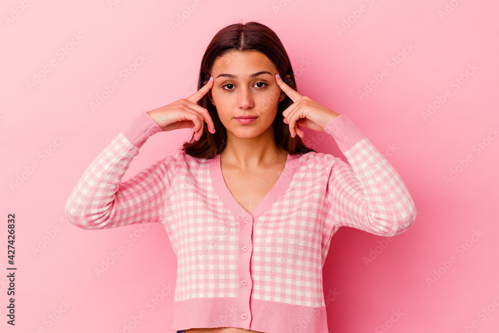 Young Indian woman isolated on pink background focused on a task, keeping forefingers pointing head. Young Indian woman isolated on pink background focused on a task, keeping forefingers pointing head.