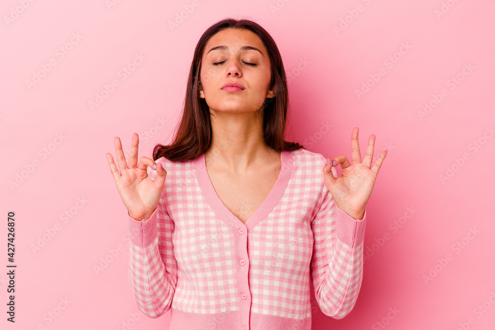 Young Indian woman isolated on pink background relaxes after hard working day, she is performing yoga. Young Indian woman isolated on pink background relaxes after hard working day, she is performing yoga.