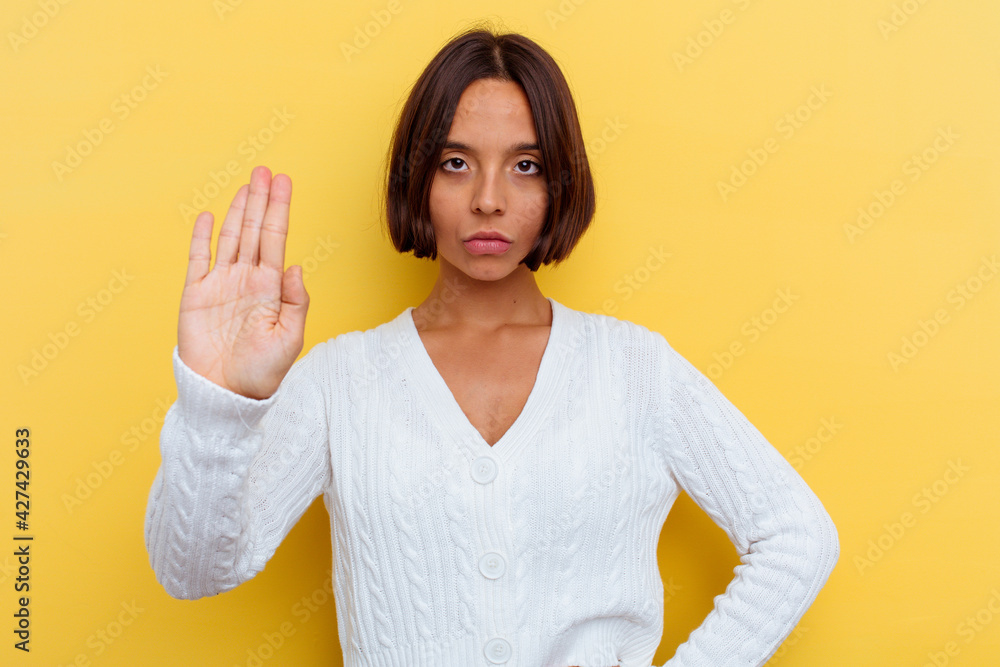 Young mixed race woman isolated on yellow background standing with outstretched hand showing stop sign, preventing you. Young mixed race woman isolated on yellow background standing with outstretched hand showing stop sign, preventing you.