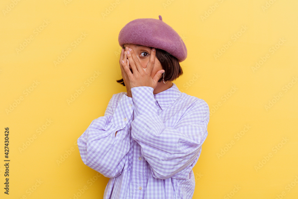 Young mixed race woman wearing a beret isolated on yellow background blink through fingers frightened and nervous. Young mixed race woman wearing a beret isolated on yellow background blink through fingers frightened and nervous.