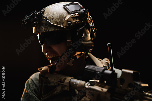 US special forces soldier looking at the aim ready to shoot against black dark background