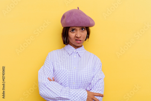 Young mixed race woman wearing a beret isolated on yellow background unhappy looking in camera with sarcastic expression.