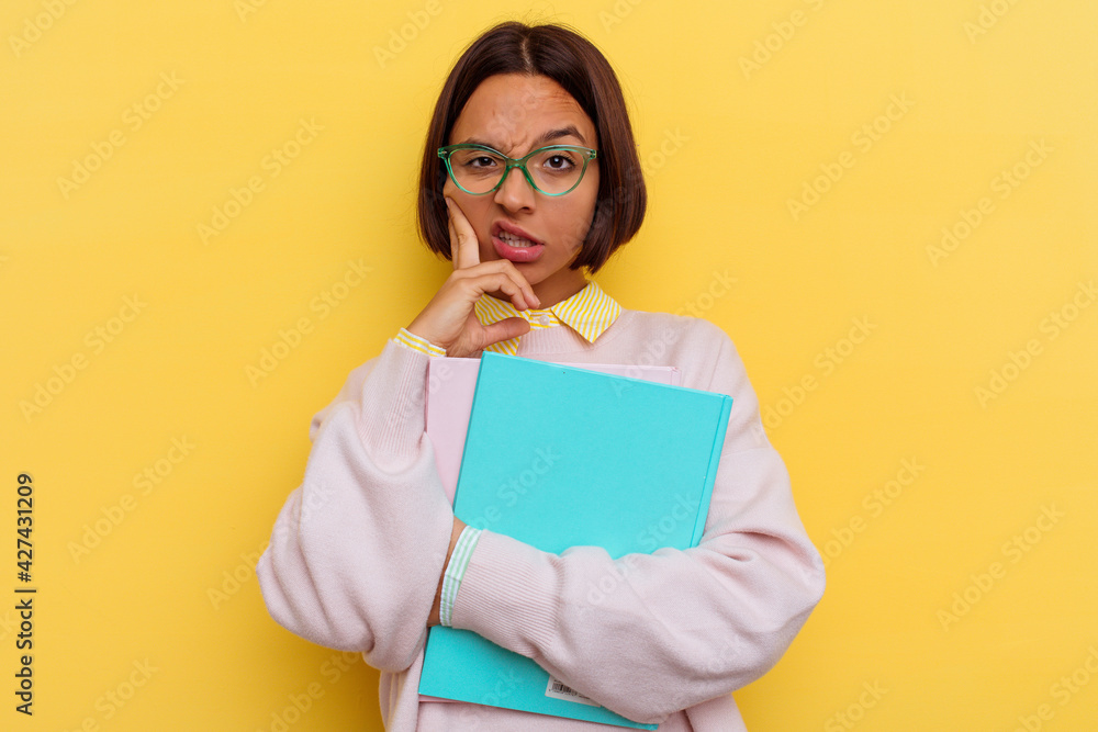 Young mixed race student woman isolated on yellow background Young mixed race student woman isolated on yellow background