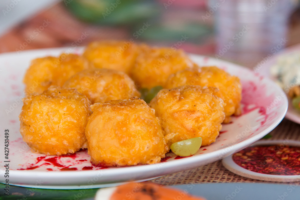 Breaded chicken nuggets, ready to eat on a plate. On a table with a bright background.