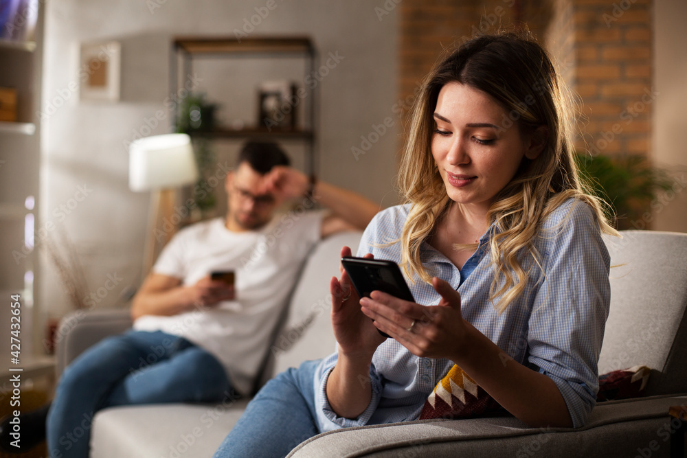 Happy young woman using the phone at home. Excited woman enjoying in the living room.