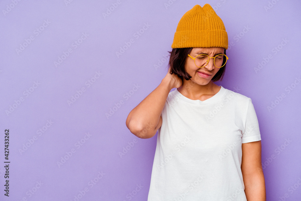 Young mixed race woman wearing a wool cap isolated on purple background touching back of head, thinking and making a choice.